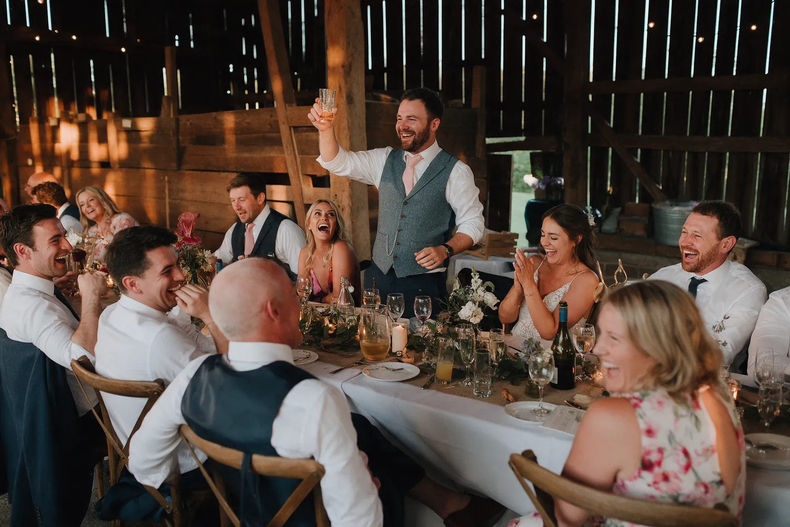 Guests laughing around a long table during speeches