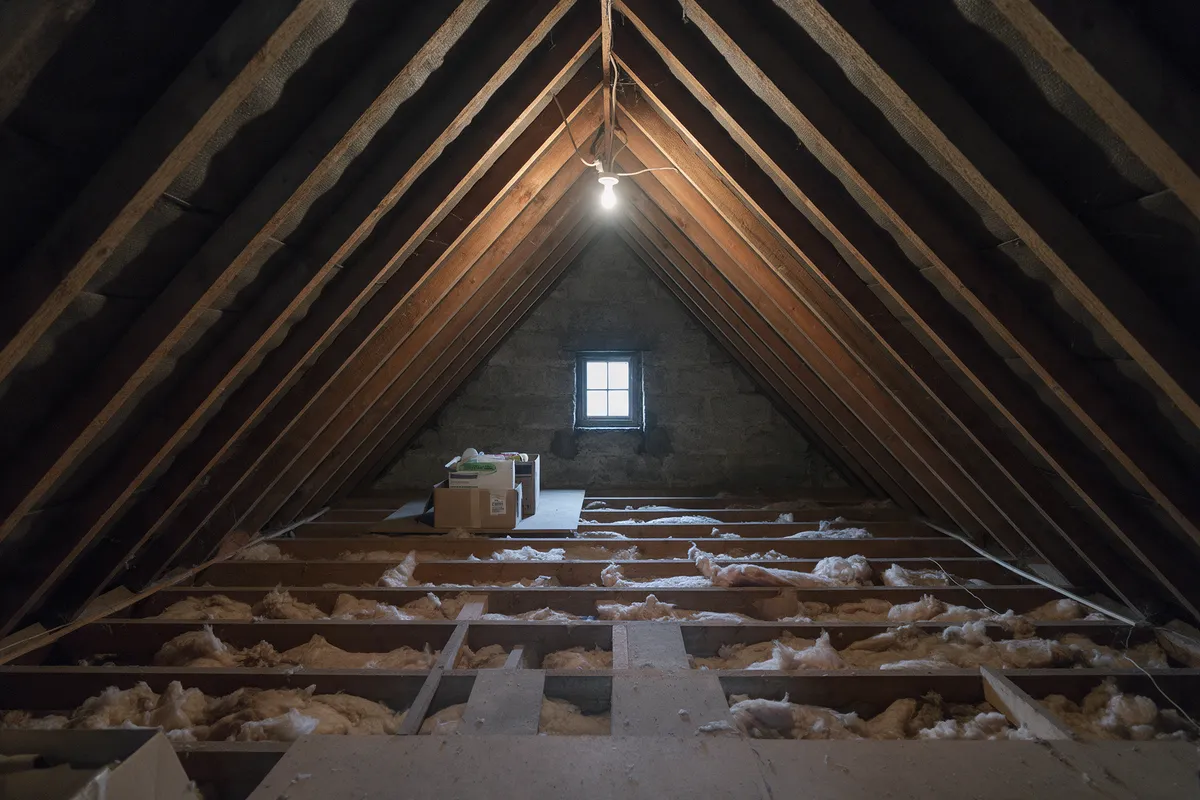 Before: an unconverted attic with exposed rafters, loose insulation and boxes