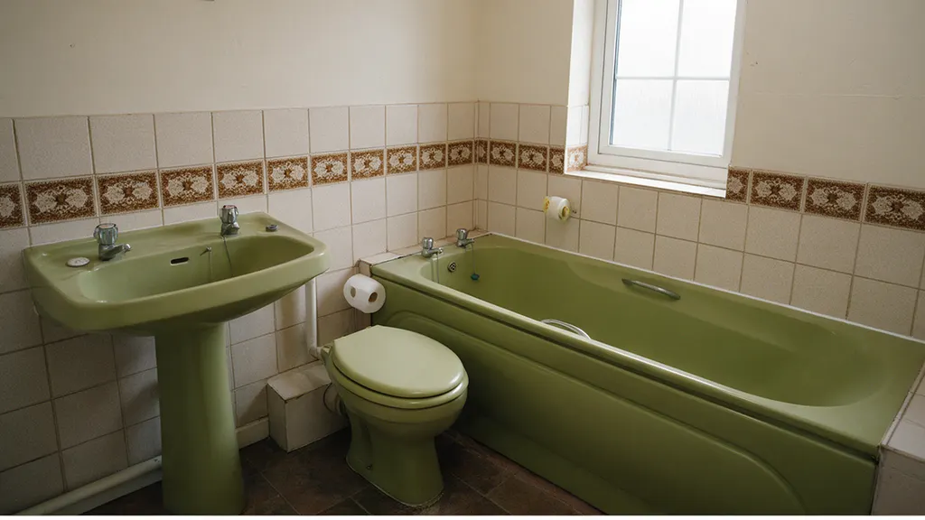 The same bathroom before: an avocado green suite with brown border tiles