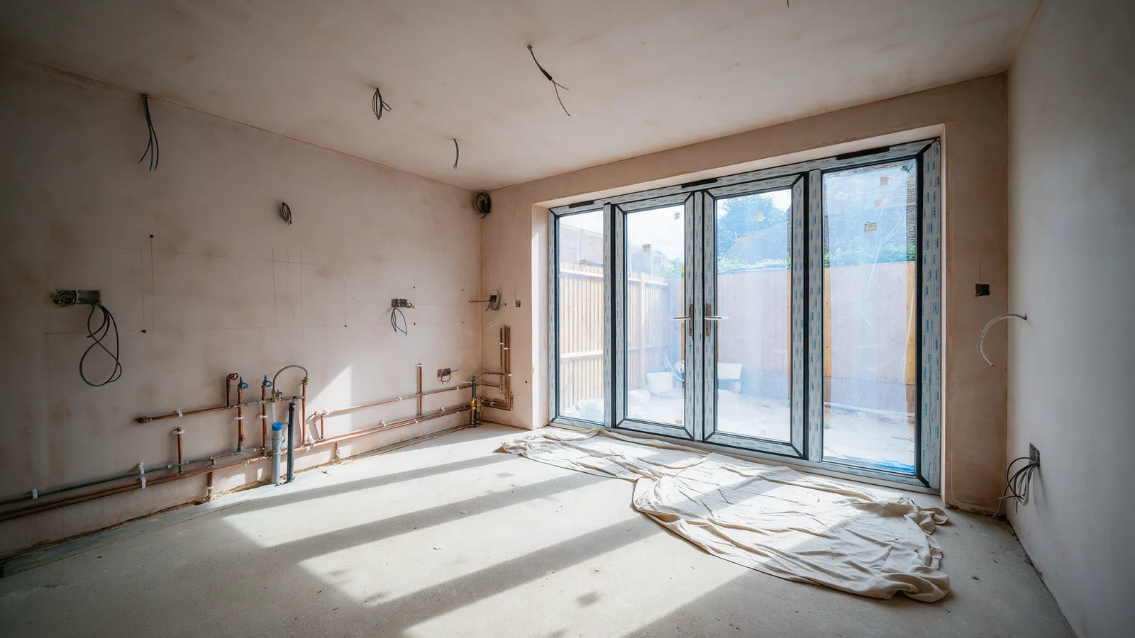 The same extension before: bare plaster, first-fix pipes and a concrete floor
