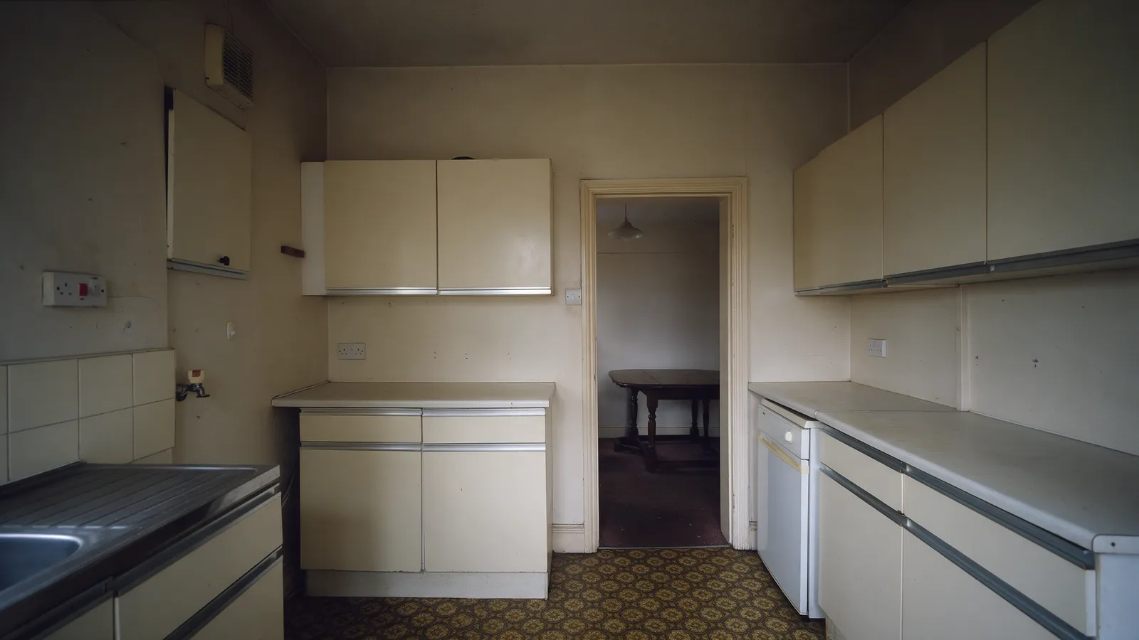 The same back room before: a small separate kitchen and a dining room with a wall between