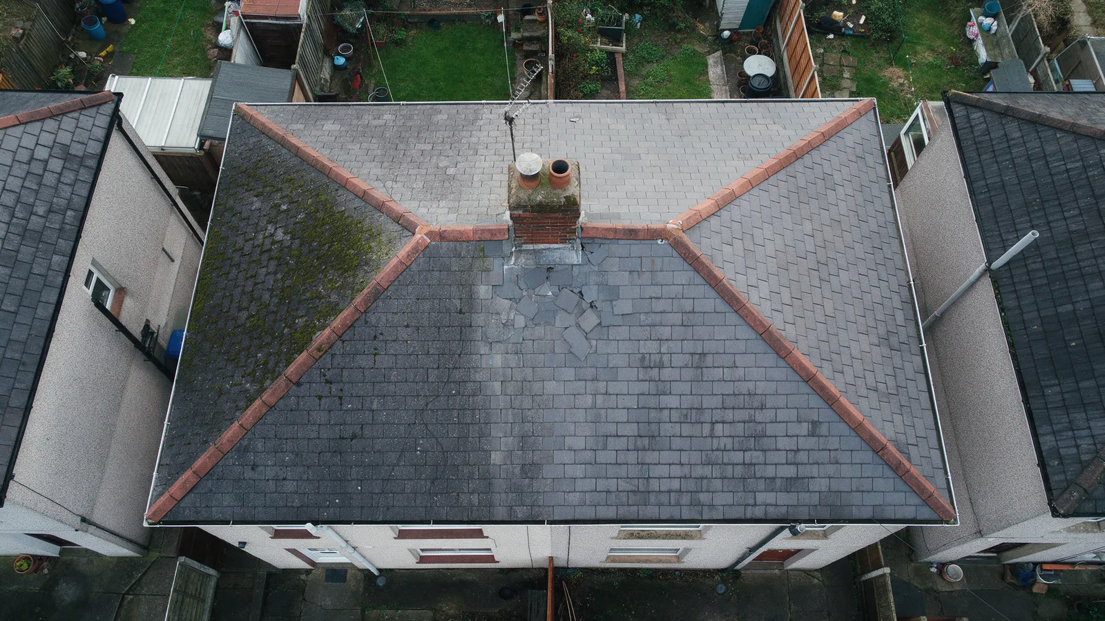 Aerial drone photograph of a slate roof with slipped slates near the chimney and moss on the north slope