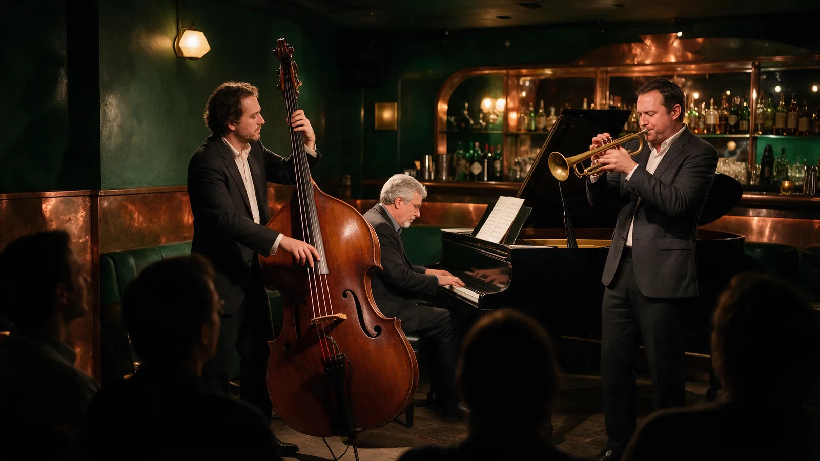 A jazz trio with double bass, piano and trumpet playing in the corner of a dimly lit green and copper cocktail bar