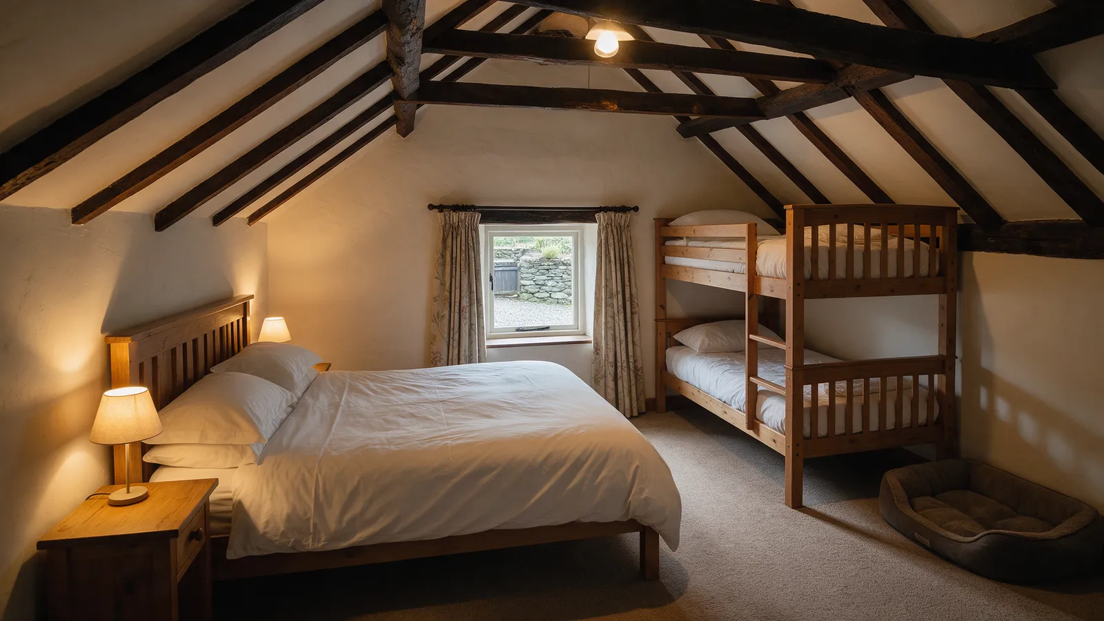 A family room in a converted hayloft: a double bed and a pair of wooden bunks under a sloping beamed ceiling, a small window onto a yard, a dog bed in the corner
