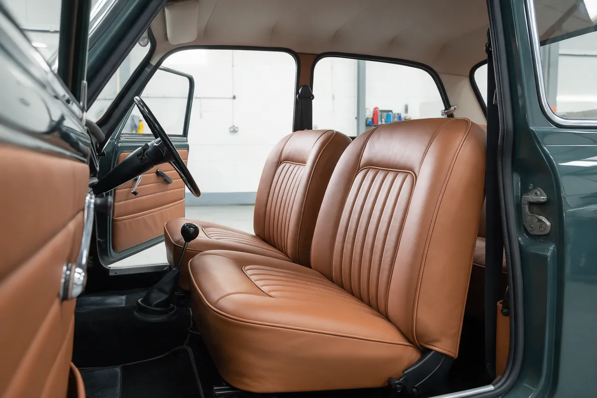 A classic 1960s British car interior re-trimmed in tan leather with contrast piping, seen through the open door