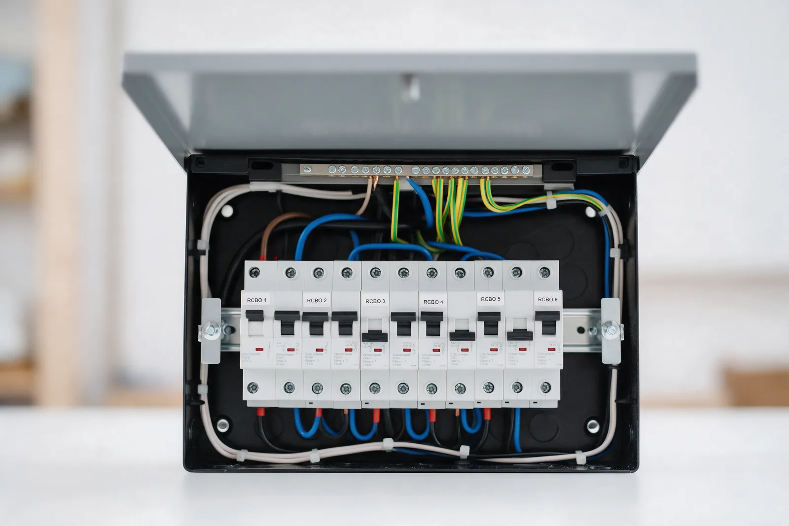 A new metal consumer unit with its cover open showing a row of labelled RCBOs