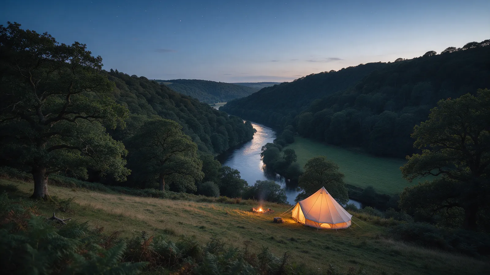 The wooded Wye valley at dusk seen from a hillside meadow, the river glinting below, a bell tent glowing at the edge of the field